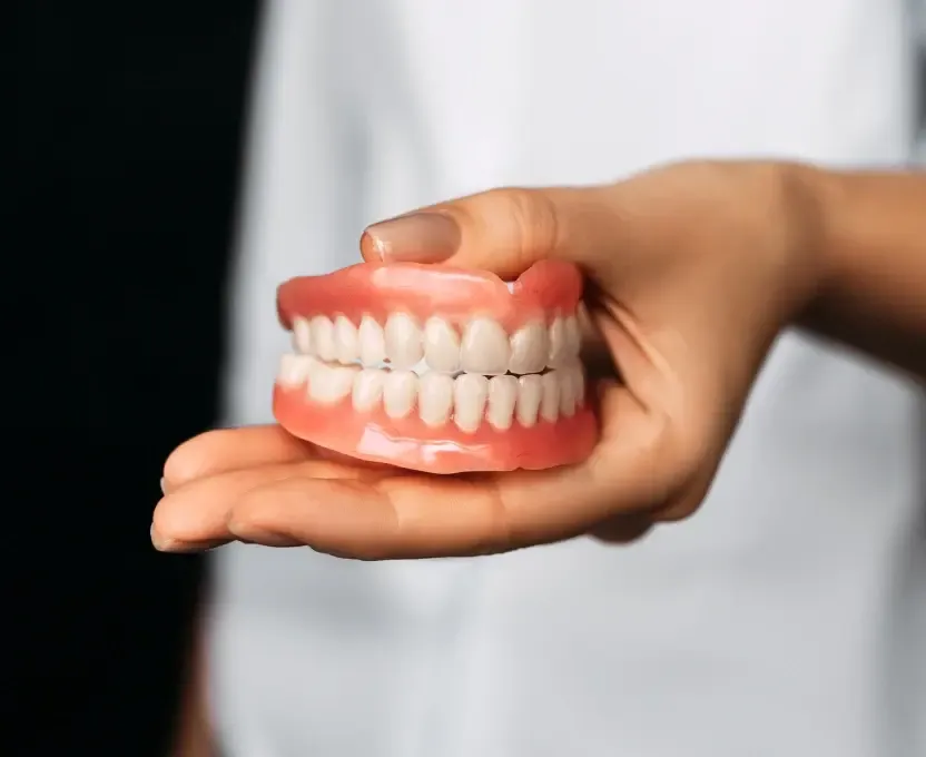 Dentist holding a custom full denture at a Cedar Park dental office